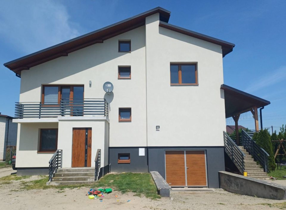 Dom w Koprzywnicy po termomodernizacji — elewacja ocieplona styropianem 15 cm, nowe drzwi wejściowe i garażowe