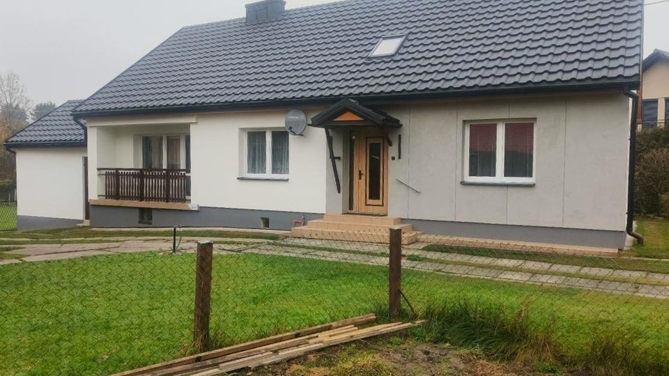 Dom w Zatorze po termomodernizacji — elewacja ocieplona styropianem grafitowym 12 cm i nowe drzwi wejściowe